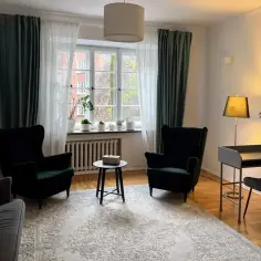 Eleganckie fotele, biurko i lampa w jasnym wnętrzu z oknem.